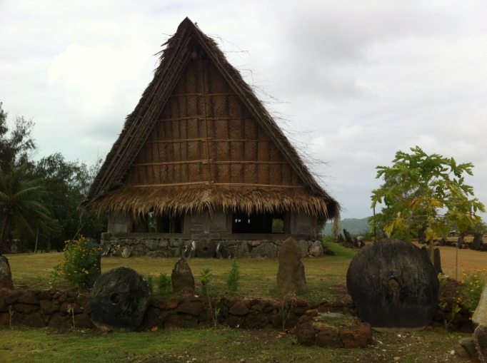 a traditional Yapese house and some stone money around it